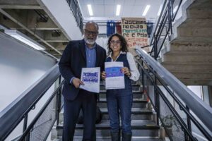 A pesquisadora Karina Quintanilha entrega o relatório do projeto Fronteiras Cruzadas para Jorge Amâncio de Oliveira, Pró-Reitor de Cultura e Extensão da USP.