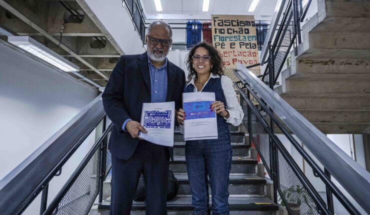 A pesquisadora Karina Quintanilha entrega o relatório do projeto Fronteiras Cruzadas para Jorge Amâncio de Oliveira, Pró-Reitor de Cultura e Extensão da USP.